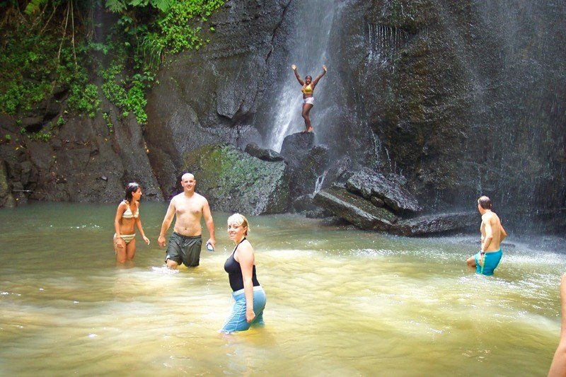 Guests swimming beneath a Saint Lucia waterfall